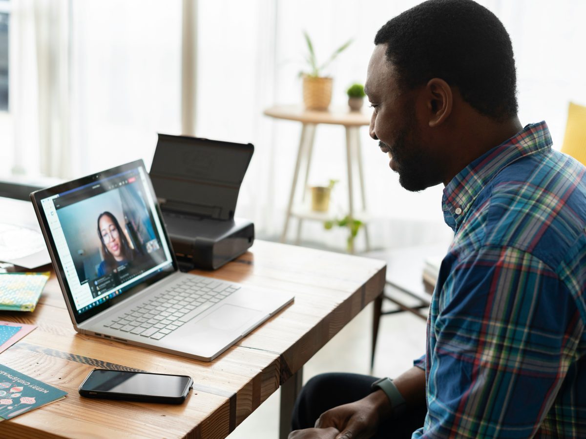 A man sitting at his desk in an office, engaged in a virtual video call on his laptop.