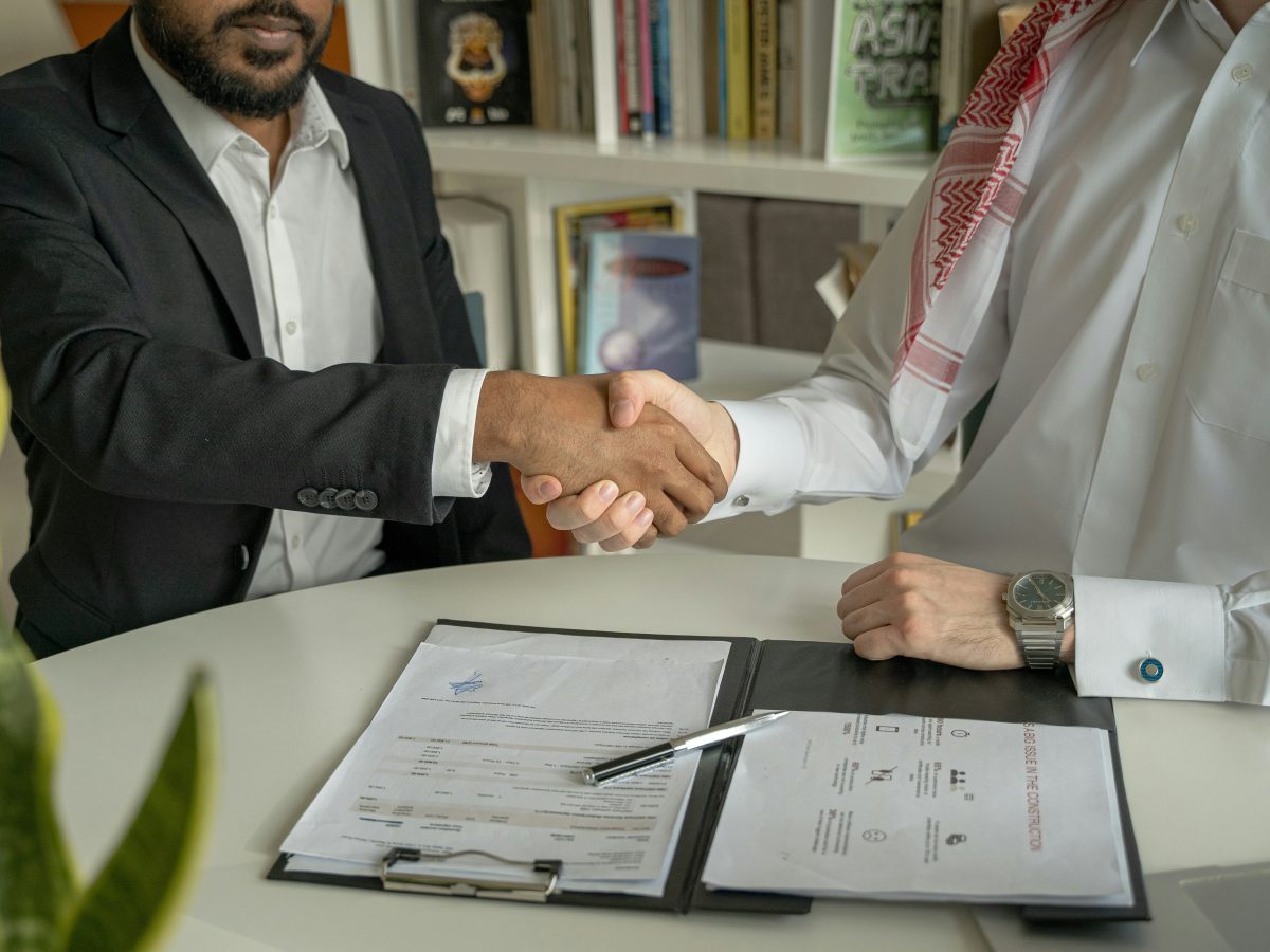 Two males shaking hands over a contract that has just been signed