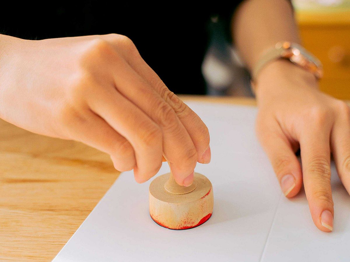 Person stamping a certificate on a desk